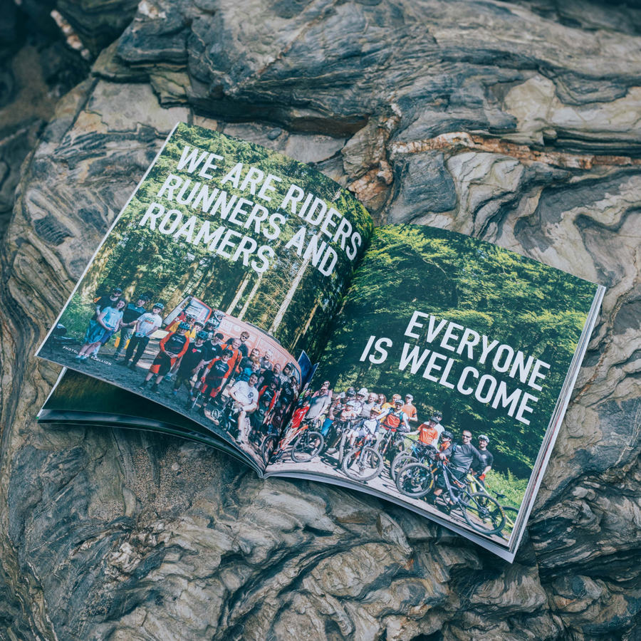 Trash Free Trails Sidetracked Magazine placed on a wooden background. The magazine front cover shows a man on a bike surronded by countryside. 